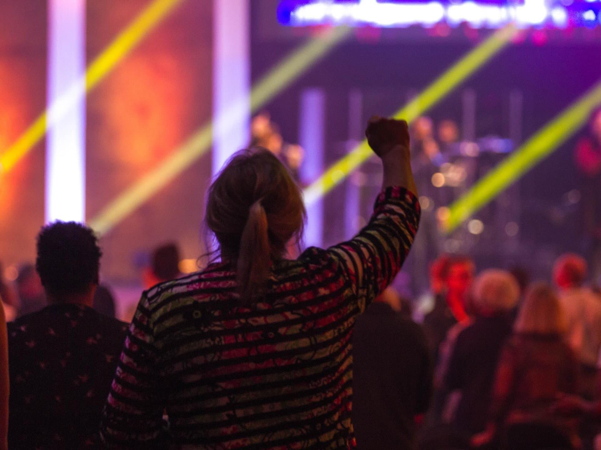 Woman watching a concert with right arm in the air