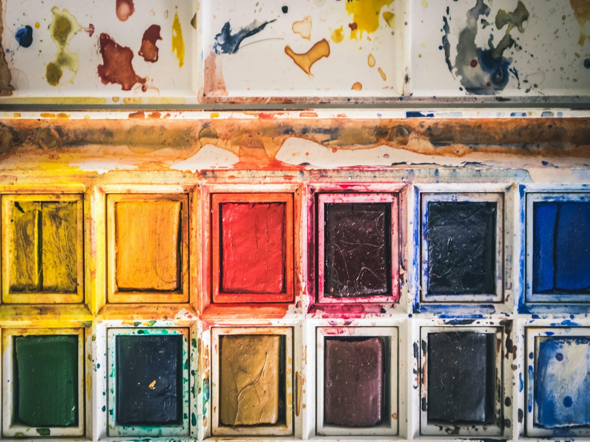 Colourful close-up of used watercolor paint palette with vibrant hues