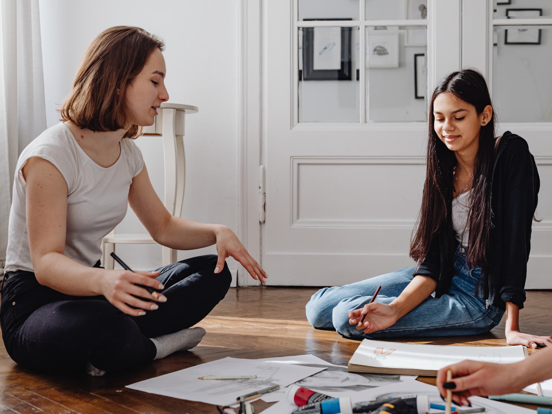 Two people sat on the floor between art supplies